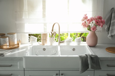 Vase with flowers on countertop near sink against window in kitchen
