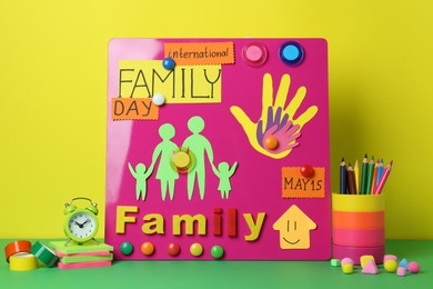 Happy International Family Day. Composition with stationery on green table against yellow background