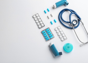 Flat lay composition with stethoscope, asthma medications and space for text on white background