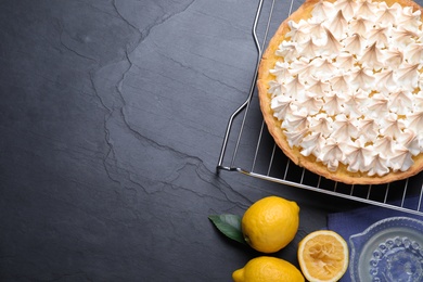 Flat lay composition with delicious lemon meringue pie on black table. Space for text