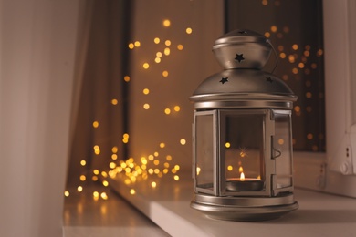 Photo of Decorative Christmas lantern with burning candle on windowsill. Space for text