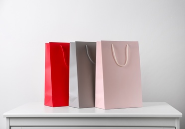 Paper shopping bags on white table against light background