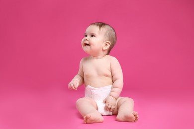 Cute little baby in diaper sitting on pink background