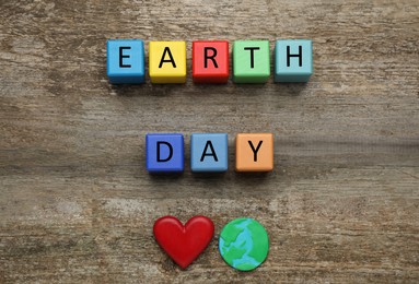 Colorful cubes with words Earth Day, decorative heart and plasticine planet on wooden table, flat lay