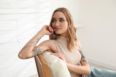 Beautiful woman with tattoos on arms resting at home