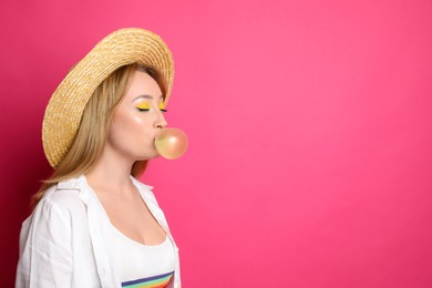 Fashionable young woman with bright makeup blowing bubblegum on pink background, space for text
