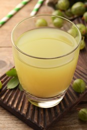 Photo of Tasty gooseberry juice and fresh berries on wooden table, closeup
