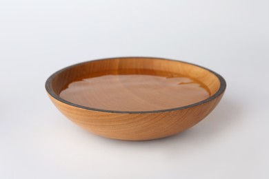 Wooden bowl full of water on white background