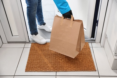 Courier bring paper bags with takeaway food to doorway, closeup. Delivery service during quarantine due Covid-19 outbreak