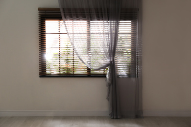 Window with beautiful curtain and blinds in empty room