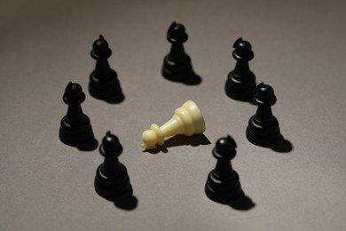 Black chess pieces and white one on grey background. Bullying concept