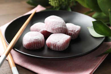 Black plate with delicious mochi and chopsticks on wooden table. Traditional Japanese dessert