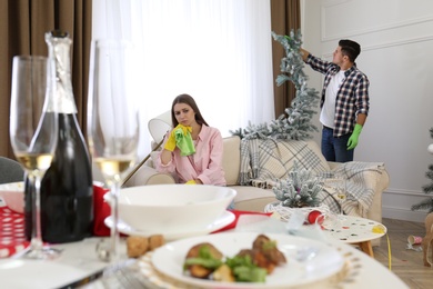 Couple cleaning messy room after New Year party