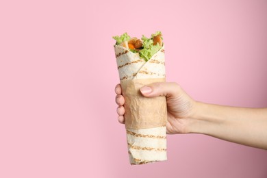 Photo of Woman holding delicious chicken shawarma on pink background, closeup