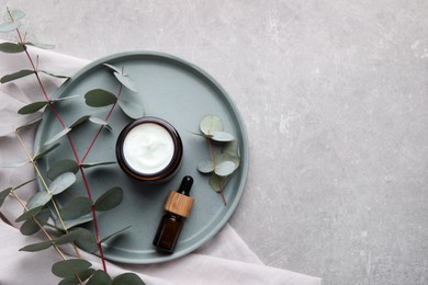 Different hand care cosmetic products and eucalyptus branches on grey table, flat lay. Space for text