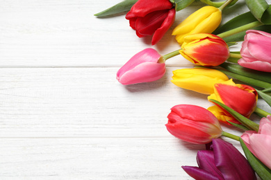 Beautiful spring tulips on white wooden table, flat lay. Space for text
