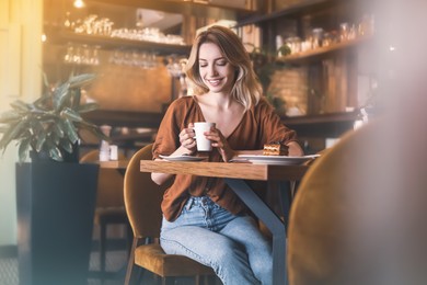 Young woman with cup of coffee at cafe in morning