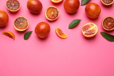 Many ripe sicilian oranges and leaves on pink background, flat lay. Space for text