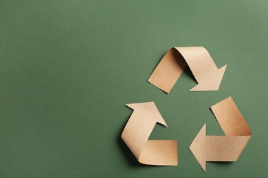 Recycling symbol cut out of kraft paper on green background, top view. Space for text