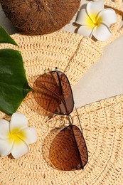 Flat lay composition with stylish sunglasses and wicker bag on sand
