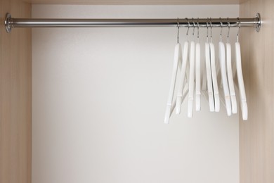 Set of wooden clothes hangers on wardrobe rail. Space for text
