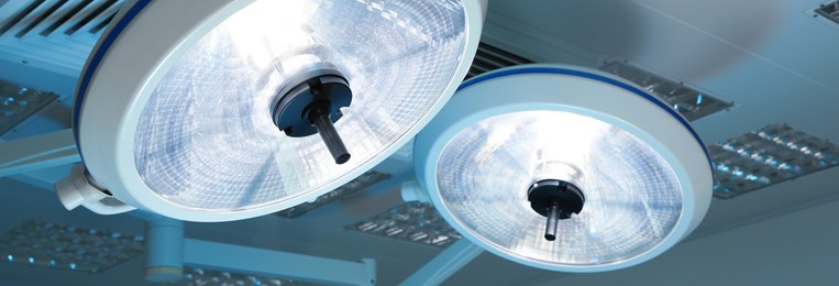 Image of Powerful surgical lamps in modern operating room, closeup. Banner design