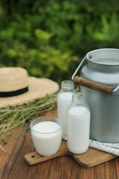 Fresh milk on wooden table outdoors. Space for text