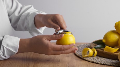 Photo of Woman zesting lemon at wooden table, closeup