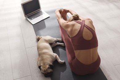 Woman with dog following online yoga class at home, above view