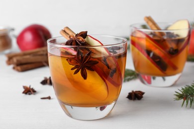 Hot mulled cider, ingredients and fir branches on white wooden table