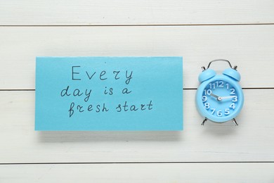 Phrase Every Day Is A Fresh Start and alarm clock on white wooden table, flat lay. Motivational quote
