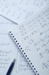 Notebook with different mathematical formulas and pen, top view