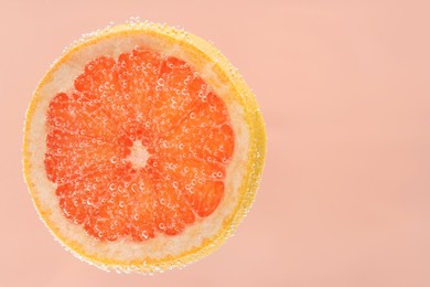 Slice of grapefruit in sparkling water on light pink background. Citrus soda
