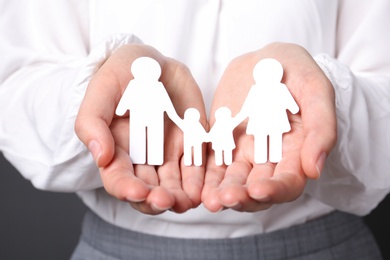 Woman holding cutout paper family, closeup. Life insurance concept