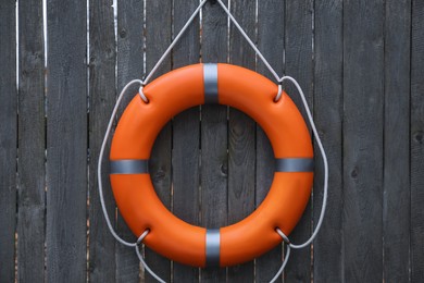 Orange lifebuoy hanging on grey wooden fence. Rescue equipment