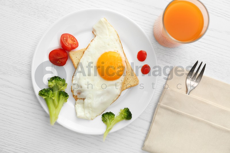 Tasty fried eggs with vegetables and juice on white wooden table, flat lay. Delicious morning meal