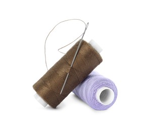Different colorful sewing threads and needle on white background