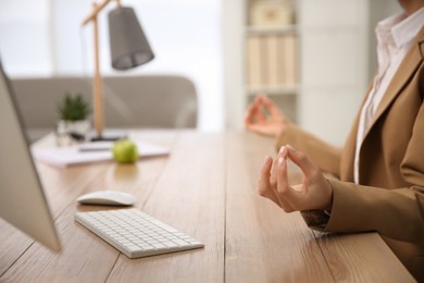 Woman meditating at workplace in office, closeup. Space for text