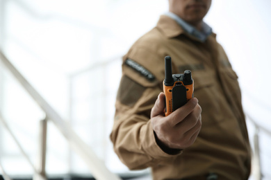 Professional security guard with portable radio set indoors, closeup