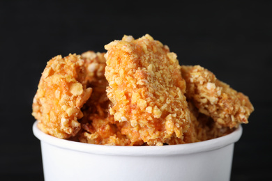 Photo of Bucket with yummy nuggets on dark background, closeup