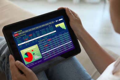 Woman analyzing electronic trading platform on tablet indoors, closeup. Stock exchange