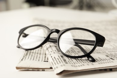 Newspapers and glasses on white table, closeup