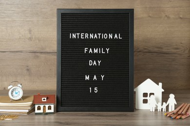 Letter board with text International Family Day May 15, decorative houses and stationery on wooden table
