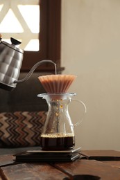 Photo of Preparing coffee at wooden table in cafe, closeup