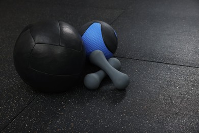 Photo of Medicine balls and dumbbells on black floor