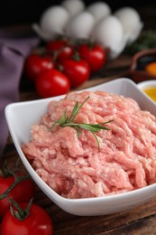 Raw chicken minced meat with rosemary on wooden table, closeup