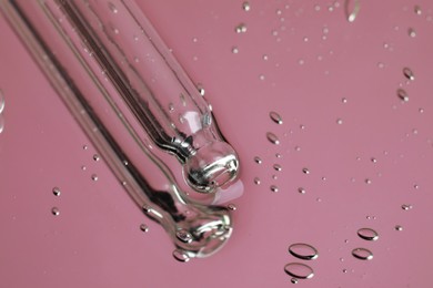 Photo of Pipette near serum drops on beautiful mirror, closeup with space for text. Toned in pink