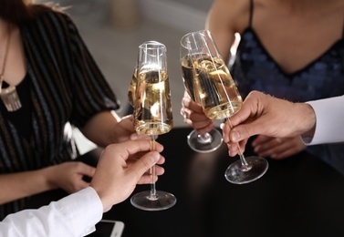 Friends clinking glasses of champagne in restaurant, closeup