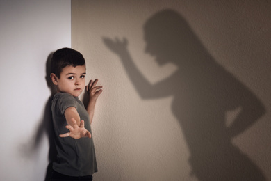 Image of Child abuse. Mother yelling at her son. Shadow of woman on wall