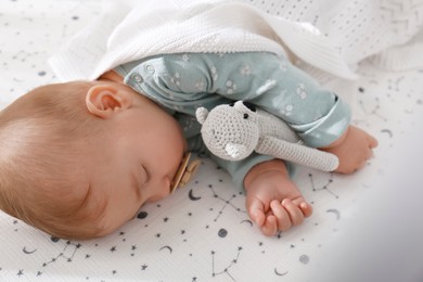 Adorable baby with toy peacefully sleeping in bed